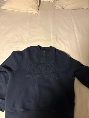 Mörkblå sweatshirt från Armani Exchange - Snygg mörkblå sweatshirt från Armani Exchange med tryckt logga och text på bröstet. Tröjan har rund halsringning och är tillverkad i mjukt bomullsmaterial. Perfekt för en avslappnad och trendig look.