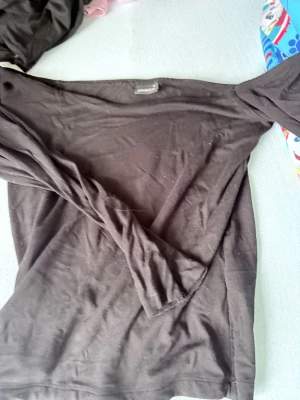 Svart långärmad topp Gina Tricot offshoulder - En enkel  svart långärmad topp från Gina Tricot. Toppen är tillverkad i mjukt material som känns skönt mot huden