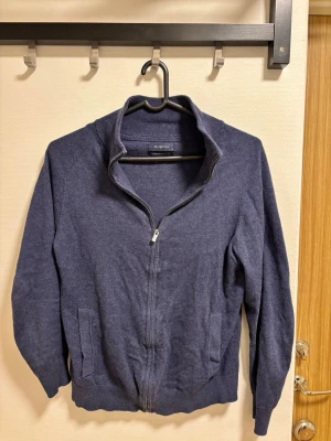 Mörkblå ziptröja i cashmere material  - Mörkblå stickad ziptröja från Dustin med hög krage och hel dragkedja framtill. Tröjan har två fickor och ribbade muddar vid ärmslut och nederkant. Perfekt för lager-på-lager och enkel att matcha med andra plagg.