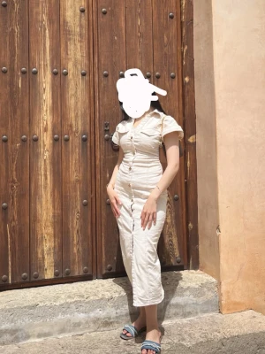 Beige knappklänning med puffärm - Snygg beige långklänning med korta ärmar och v-ringning. Klänningen har knappar hela vägen framtill  och är i storlek S. jag brukar ha storlek xs på mig men den passar perfekt som det syns på bilden. Använt en gång utomlands. Perfekt för varma dagar och har en figurnära passform som framhäver siluetten. Är köpt från Zara.