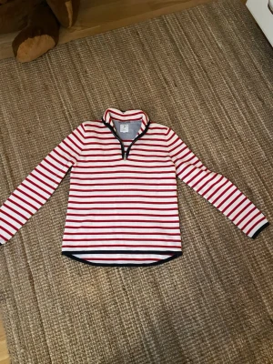 Randig tröja jätte fin till sommaren  - Säljer en långärmad tröja med röda och vita horisontella ränder. Tröjan har en liten krage framtill samt mörkblå kant vid krage och nederkant. Så fin 