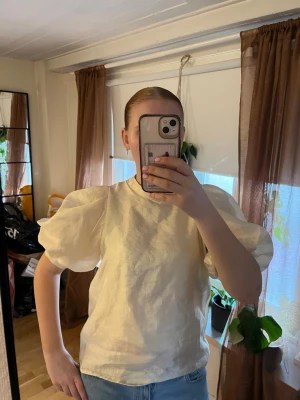 Gul blus med puffärmar - Snygg ljusgul blus med glansigt tyg och stora puffärmar. Perfekt för dig som vill sticka ut med en trendig och elegant look. Använd fåtal gånger 