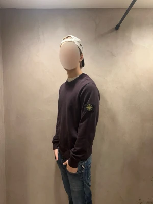 Mörklila sweatshirt från Stone Island - Säljer en mörklila sweatshirt från Stone Island med den klassiska logotypen på vänster ärm. Tröjan har rund halsringning, ribbade muddar och är tillverkad i en mjuk bomullsblandning. Perfekt för en avslappnad och stilren look. Tröjan har inga defekter men har nån fläck på magen, som förmodligen går bort i tvätt.