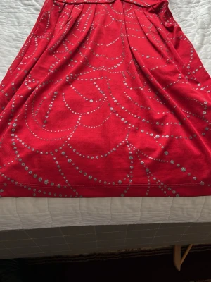 Röd klänning med silverprickar - Snygg röd klänning från H&M med glittriga silverprickar i ett mönster över hela tyget. Klänningen har en mjuk och följsam känsla, perfekt för dig som vill sticka ut. Passar dig som gillar färg och glitter.
