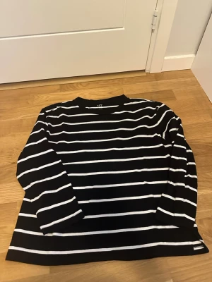 Svartvit randig topp från 157 Oversized stl M - Randig långärmad topp från 157 i svart och vitt. Tillverkad i 100% bomull med klassisk rund halsringning och raka ärmar. Perfekt för dig som gillar enkel och stilren design med en avslappnad vibe.