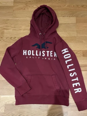 Vinröd hoodie från Hollister - Superfin hoodie i bra skick! Skriv till mig vid frågor svarar snabbt! Eller om ni vill ha måtten så löser jag också det!