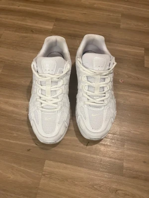 Vita Nike sneakers mesh och läder - Säljer ett par helvita Nike sneakers med lågt skaft. Skorna har en chunky sula, ovandel i mesh och läderdetaljer samt klassisk Nike Swoosh på sidan. Perfekta för dig som gillar sportig och clean stil. Skosnören i vitt och ventilerande material.