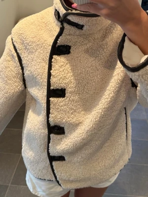 Beige teddyjacka med svarta detaljer - Säljer denna jätte trendiga teddy jacka från H&M💕helt slutsåld på hemsidan! Nypris 550kr