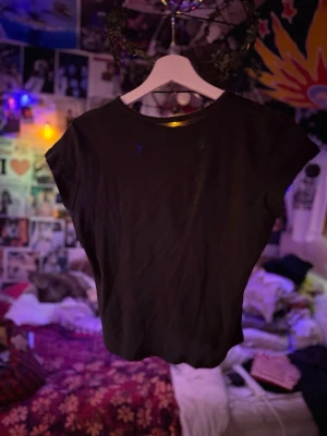 Svart croppad t-shirt Brandy Melville - En svart croppad t-shirt från Brandy Melville med rund halsringning och korta ärmar. Tillverkad i mjuk bomull som känns skön mot huden. Enkel och clean design som passar till allt.