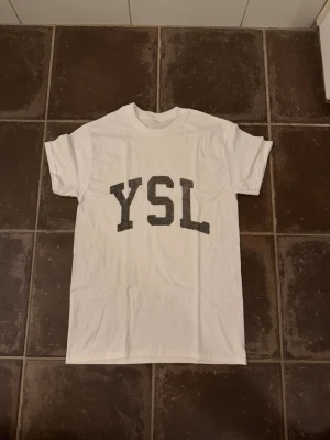 YSL t shirt - Riktigt fet och eftertraktad t shirt med YSL loggan i storlek S! Helt nytt skick! Lite osäker på äktheten eftersom lappen i nacken saknas så därför är priset just nu på 499kr nypris runt 3000kr! Tveka inte med att ställa frågor! 