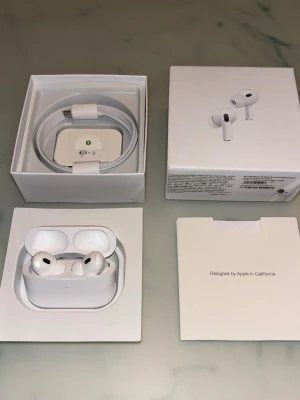 Apple AirPods Pro 2nd generation trådlösa hörlurar - Säljer ett par vita Apple AirPods Pro med magsafe laddning och USB-C kabel. Hörlurarna har in-ear design med silikonproppar och stilren, kompakt form. Perfekta för dig som vill ha grymt ljud och smidig anslutning till din iPhone eller andra Apple-enheter.