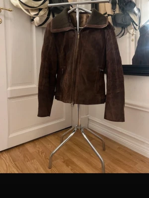 Brun oversized skinnjacka - Säljer en brun oversized skinnjacka med bred krage och dragkedja framtill. Jackan har två fickor med dragkedja och en avslappnad passform som ger en cool vintagekänsla. Perfekt för dig som gillar en lite tuffare stil.