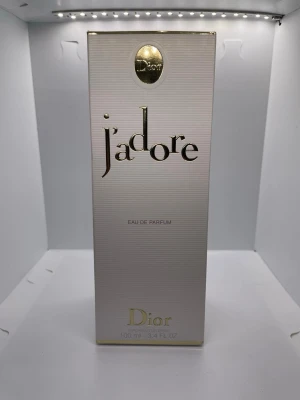 J'adore Eau de Parfum 100ml från Dior - J'adore Eau de Parfum från Dior i elegant 100ml flaska. Flaskan är droppformad med guldfärgade detaljer och en unik kork i glas och guld. Doften är ikonisk och lyxig, perfekt för dig som vill ha något klassiskt och exklusivt i parfymhyllan.