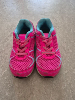 Sneakers - Snygga sneakers i starkt rosa mesh med turkosa detaljer och vita inslag. Skorna har snörning och en sportig design med ventilerande material och vadderad insida. Perfekta för dig som gillar färg och vill sticka ut. Sulan är vit med turkosa partier.