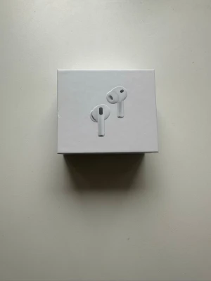 Apple AirPods Pro trådlösa hörlurar - Säljer ett par vita Apple AirPods Pro med laddningsetui. Hörlurarna har en stilren och kompakt design i blank plast och levereras i originalförpackning. Perfekta för dig som vill ha grymt ljud och smidig anslutning till din iPhone eller andra Apple-enheter.