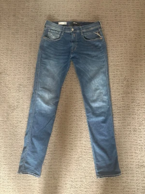 Blå slim fit jeans från Replay - Snygga blå slim fit, anbass hyperflex jeans från Replay med klassisk femficksdesign och dragkedja. Väldigt stilrena jeans som går att kombinera med nästintill alla kläder. Nypris 1599:-, kontakta vid frågor. 