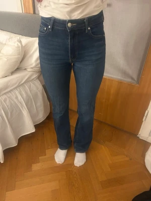 Mörkblå raka jeans - Säljer ett par mörkblå jeans med rak passform.  Klassisk femficksmodell med silverfärgade knappar och dragkedja. Materialet är denim i bomull.