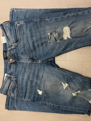 Blå slitna jeans från Jack and Jones - Säljer ett par blå jeans från Jack and Jones med snygga slitningar och hål på framsidan. Klassisk femficksmodell med raka ben och normalhög midja. Jeansen har en cool, avslappnad vibe och är perfekta för en trendig Grish look. Dom säljs för ett mycket bra pris men kan diskuteras. Skriv vid minsta fundering!!🤩🤩