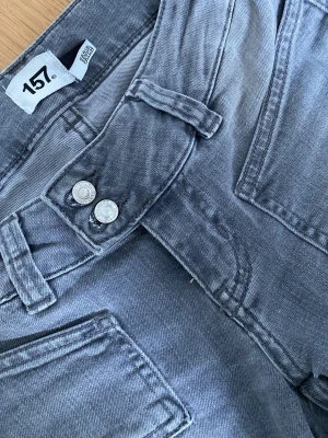 Grå jeans med dubbla knappar från lager 157 - Säljer ett par grå jeans från lager 157 med dubbla knappar i midjan. De är utsvängda med lågmidja. 