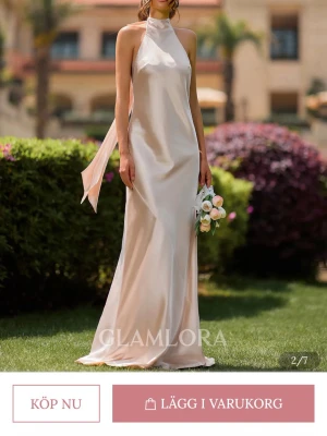 Champagne/puderfärgad balklänning i satin - Elegant långklänning i champagne/puderfärgad satin från Glamlora. Klänningen har halterneck, öppen rygg och ett långt band som knyts i nacken. Siluetten är slank och materialet skimrar snyggt i ljuset. Perfekt för dig som vill ha en stilren och lyxig look. Passar för en som är minst 170 cm lång. 