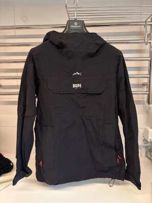 Täckjacka dope - Svart täckjacka/ vindjacka från Dope! Endast använd 1 gång. Inga slitningar. Storlek XS men passar även S. Går att dra åt där nere. 