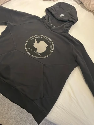 Svart Hoodie Sail Racing - Svart hoodie med stor rund logga på bröstet av Sail Racing