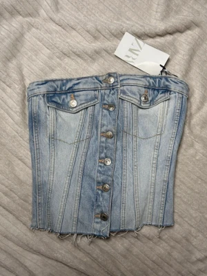 Jeanstopp Zara  - Ljusblå jeans topp från Zara, ny med prislapp. Storlek s men passar även xs.  Köp sker via köp nu, jag postar inom 24h. Kvar tills markerad såld