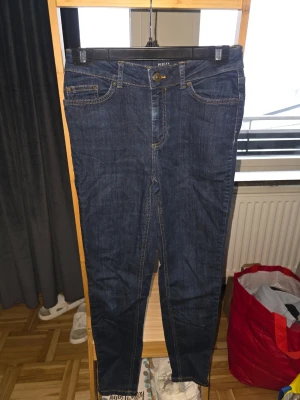 Mörkblå skinny jeans från Pieces - Snygga mörkblå skinny jeans från Pieces med klassisk femficksmodell och kontrastsömmar. Jeansen har normal midja och dragkedja med knapp framtill. Perfekta till en avslappnad stil och passar till det mesta.