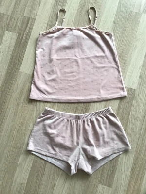 Ljusrosa pyjamasset (linne och shorts) i plysch, stl 146/152 - Sött ljusrosa pyjamasset med linne och matchande shorts. Setet har tunna axelband och är gjort i plysch med små diskreta stjärnor på. Har varit en favorit, så välanvänt set, men funkar absolut till en ny ägare, nu när jag växt ur den. Just nu fri frakt, så du betalar bara för pyjamasen. Jag har fler plagg ute, och hittar du något mer från min garderobsutrensning, så skickar jag allt i samma paket.
