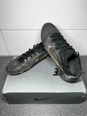 Nike Mercurial Vapor 14 Elite FG svart/guld fotbollsskor - Säljer ett par Nike Mercurial Vapor 14 Elite FG i svart med stilrena gulddetaljer. Det är Elite-modellen (toppmodellen) med FG-dobbar, anpassade för naturgräs och konstgräs   Använda men i bra skick – se bilder för detaljer. Perfekta för både träning och match. Säljs med originalkartong.  Ordinarie pris 2799  Hör av dig vid frågor eller om du vill ha fler bilder 😊 