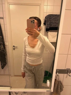 Vit långärmad topp - Vit långärmad topp i ribbat material med v-ringad hals och dekorativ spetskant. Använd fåtal gånger! Nypris: 299kr