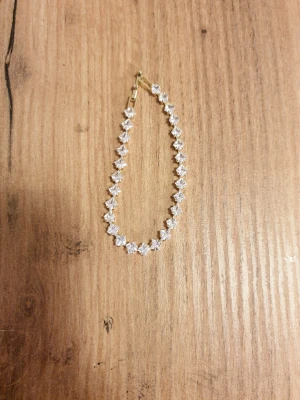 Guldarmband med fyrkantiga stenar - Snyggt armband i guldfärgad metall med gnistrande, fyrkantiga klara stenar längs hela bandet. Armbandet har ett elegant och stilrent uttryck med diskret lås. Perfekt för dig som gillar bling och vill addera lite extra shine till din look.