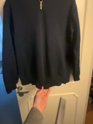 Svart halfzip hoodie från Zara - Snygg svart hoodie från Zara med halfzip-dragkedja framtill. Klassisk modell med långa ärmar och ribbade muddar. Tillverkad i mjukt material som känns skönt mot huden. Perfekt för en chill och stilren look.