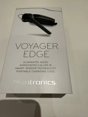 Plantronics Voyager Edge headset - Snyggt och smidigt svart Bluetooth-headset från Plantronics, modell Voyager Edge. Headsetet har smart sensor-teknologi, brusreducering och portabelt laddningsetui. Perfekt för samtal på språng och enkel att bära med sig tack vare den kompakta designen.