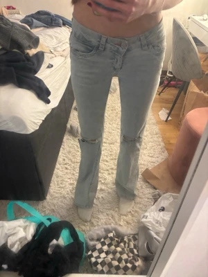Nelly stich ljusblåa jeans - Säljer ett par ljusblå bootcut jeans med slitningar vid knäna och klassisk femficksmodell. Jeansen har låg midja och är i stretchigt denimtyg. Nästan aldrig använda, kommer aldrig till användning därav att jag säljer jag dom 