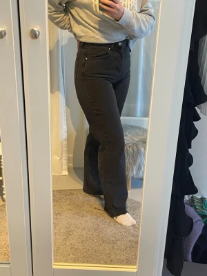 Svarta jeans med hög midja - Säljer ett par svarta jeans med hög midja och klassisk femficksdesign. Jeansen har en snygg, rak passform och stängs med knappar. Fransigt benslit. Perfekta till sneakers eller boots. W28/L32