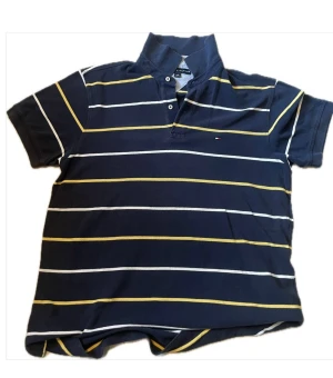 Randig piké från Tommy Hilfiger - Mörkblå pikétröja från Tommy Hilfiger med vita och gula horisontella ränder. Klassisk krage, kortärmad och med knappar framtill. Liten logga broderad på bröstet. Perfekt för en avslappnad och stilren look.