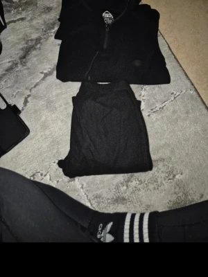 Svart loungewear-set från FJELLRÄVEN - Mysigt svart loungewear-set från FJELLRÄVEN med långärmad tröja med halv dragkedja och matchande byxor. Perfekt för chill hemma eller när du vill vara bekväm. Materialet känns mjukt och stretchigt.
