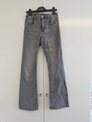 Grå jeans från KappAhl  - Snygga grå jeans i bootcut modell och hög midja. Klassisk femficksmodell med dragkedja och knapp framtill. Jeansen har en tvättad look och är perfekta för en avslappnad stil. Materialet är denim i bomull. De hade en liten fläck vid ena benet, tror dock att den är borta, de sitter väldigt snyggt. Nypris: 379 kr. Storlek 158