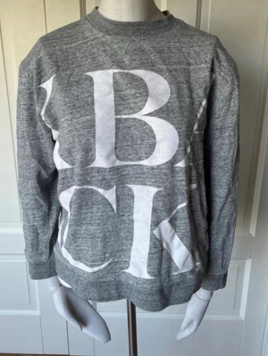 Grå sweatshirt med stor textprint - Säljer en grå sweatshirt med stor vit textprint på framsidan. Tröjan har rund halsringning. Säljer pga att den nästan aldrig används. Storleken kan upplevas som xs/s/m själv har jag storlek xs på alla kläder men passar för m också💓