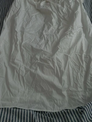 Vitt nattlinne med volang och rosett - Sött vit klänning i mjukt tyg med volangkant upptill. Lång och luftig modell som passar perfekt för mysiga kvällar hemma. Klassisk och enkel design utan mönster