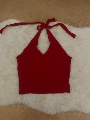 Röd ribbad halterneck topp - Snygg röd ribbad halterneck topp med knyt i nacken och v-ringad hals. Perfekt för sommaren, tycker den passar väldigt bra när man är brun på sommaren. Passar även för S då den är strechig 💕