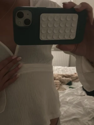 Vit omlottopp med vida ärmar - Säljer en vit omlottopp med långa, vida ärmar och lätt struktur i tyget. Toppen har en croppad passform och v-ringad hals. Perfekt för dig som gillar en stilren och trendig look.