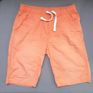 Orangea kortbyxor - Ca 76 cm midja. Aningen solblekta, några små hål i ena bakfickan och en permanent fläck där också. (Bild 3)