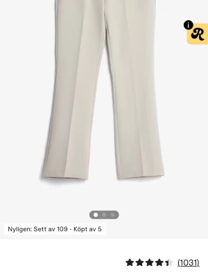 Beige kostymbyxor med pressveck - Stilrena beige kostymbyxor med pressveck och lätt utsvängda ben. Byxorna har en klassisk midja och raka linjer som ger en snygg siluett. Perfekta att matcha med en skjorta eller kavaj för en clean look.