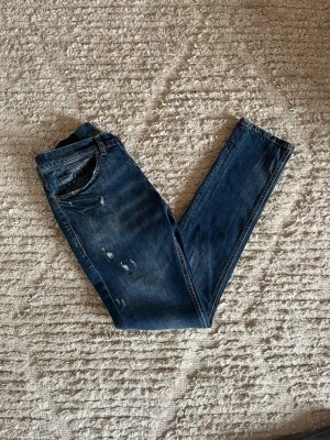 Dondup George jeans - Säljer just nu dessa otroligt feta Dondup George jeans i nyaste årsmodellen i en riktig fin blå färg med unika slitningar. Jeansen är i storlek 30. Midja 38cm. Lår 25cm. Ytterlängd 103cm. Innerlängd 80cm. Skicket på dessa är 9/10 inga skador eller defekter. För fler frågor eller funderingar är det bara att höra av sig. 