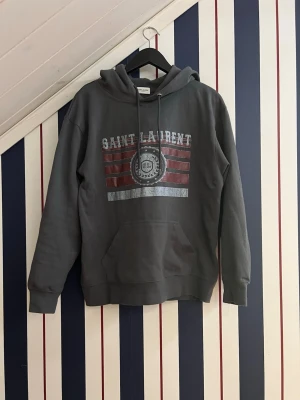 Saint Laurent hoodie - Säljer min ysl hoodie som är i storlek M. Extremt bra skick, men lite liten i storlek. Jag är 185 och den passar precis men är du runt 175-185 passar den nog dig bra. 100% bomull och den är inte supervarm så perfekt till våren och sommarkvällar. Skriv vid funderingar!