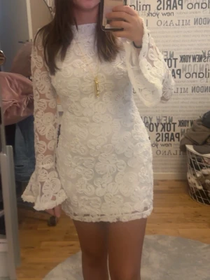 Vit blommig spetsklänning - *har storlek S på bilden‼️*                         Super fin vit klänning med mönster på!💕Långa ärmar, inte stretchig, prislappen är kvar 