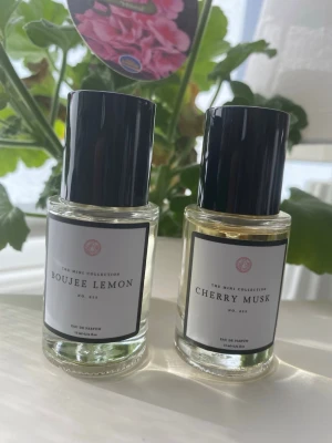 Boujee Lemon & Cherry Musk parfym - Två Eau de Parfum från The Mini Collection: Boujee Lemon och Cherry Musk. Båda flaskorna är genomskinliga med svart cylinderformad kork och vit etikett med svart ram. Doftnamnen antyder fräscha citrus- och bärtoner. Perfekt för dig som gillar unika dofter. Testade med ett fåtal sprut. Priset gäller båda tillsammans 