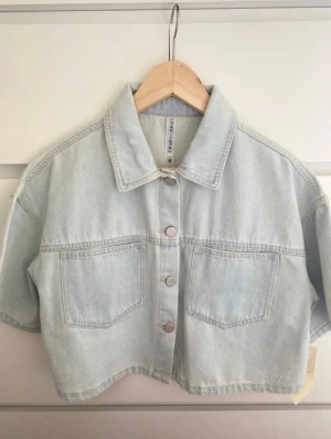 Kort ljusblå jeansjacka från Banjara - Snygg och unik jeans topp. Kan bäras som jeans skjorta och jacka. Köpt i USA men aldrig kommit till användning. Prislappen sitter kvar. Pris kan diskuteras vid snabb affär 